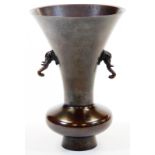 A Japanese bronze ikabana vase, with everted rim and elephant head handles, mottled reddish