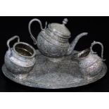 An early 20thC Indian four piece service, comprising shaped tea pot, sugar bowl and jug on an oval