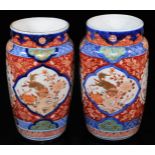 A pair of Imari porcelain vases, each of shouldered cylindrical form decorated with panels of shishi