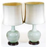 A pair of Chinese celadon porcelain lamp vases, each of bellied circular form with wooden plinths