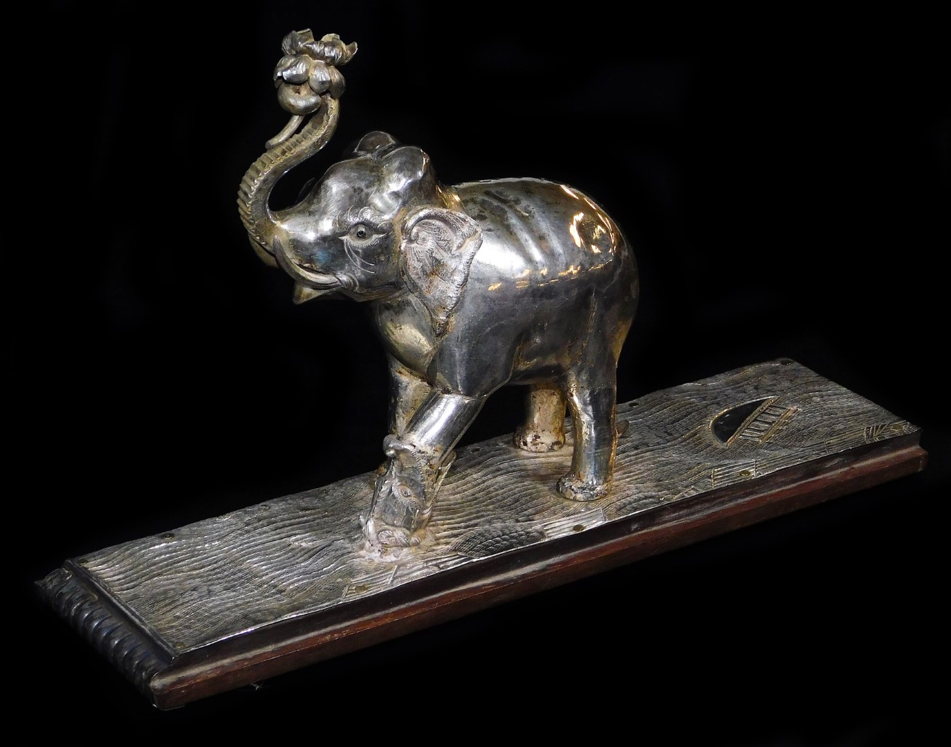 An early 20thC ceremonial figure group of an elephant being attacked by a wild beast, with trunk