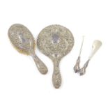 A George V silver handled button hook and shoe horn set, embossed with foliate scrolls, with