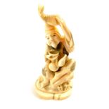 A Japanese marine ivory okimono of Ebisu, holding his carp above his head in one hand, his double