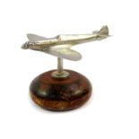 An aluminium paperweight modelled as a Spitfire, raised on a circular wooden base, 9cm wide.