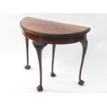 A early 20thC flame mahogany demi lune card table, with carved edge fold over top with baize