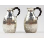 A pair of Japanese silver jugs, with leather bound handles, of bulbous form, with textured