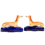 A pair of Staffordshire 19thC pottery greyhound ink wells, each modelled in recumbent pose on a blue