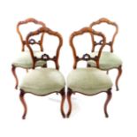 A set of four Victorian walnut carved balloon back dining chairs, with shell carved rails, studied