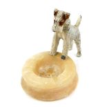 An early 20thC alabaster ashtray, surmounted with a cold painted lead figure of an Airedale terrier,