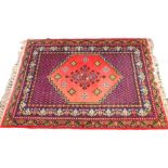 A Caucasian red ground rug, the central field decorated with floral motifs, within a border of