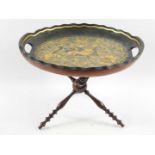 A Continental 19thC black lacquer circular twin handled tray, gilt decorated with an exotic bird,