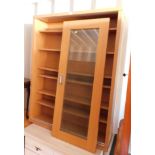 An oak effect bookcase, with two sliding glazed doors, enclosing six adjustable shelves, 131cm high,