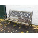 A garden bench with cast iron supports and slatted seat and lattice back, together with a wrought
