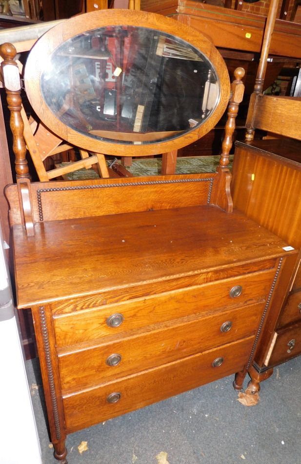 An oak early 20thC dressing chest, with oval swing mirror above three drawers, 146cm high, 91cm