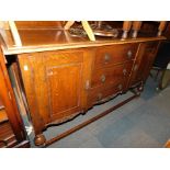 A 20thC oak sideboard, with carved back rail above three central drawers flanked by cupboards, 117cm