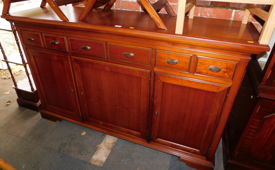 A reproduction cherry wood sideboard, with six drawers over three cupboard doors, 106cm high,