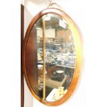 An Edwardian mahogany boxwood and inlay oval wall mirror, inset bevelled glass, 74cm high, 49.5cm