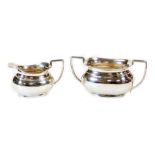 A George V silver two handled sugar bowl, 10cm high and milk jug each with angular handles of cape f