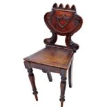 A 19thC mahogany hall chair, with castellated top, above a raised shield and scroll splat, on scroll