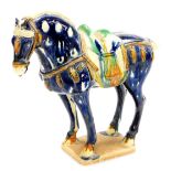 A Tang style pottery figure of a standing horse, in blue, green and orange colour way, on shaped bas