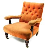 A late 19thC low armchair, with studded back and arms and overstuffed seat in peach material, with t