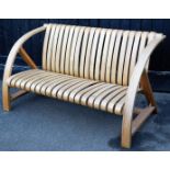 A bent wood patio settee, set with various curved slats, and shaped arms supports, 130cm wide.