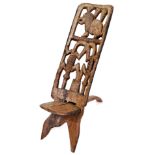 A heavily carved African tribal chair, profusely decorated with a pierced crocodile and lion back sp