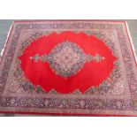 A 20thC floor standing rug, of rectangular form with a geometric floral pattern on a red ground, app