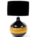 A bulbous table lamp, splash decorated with vertical gilt lines, on a yellow ground with a black sha