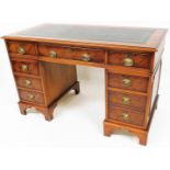 A late 20thC yew wood twin pedestal desk, the rectangular moulded top with a tooled leather section,