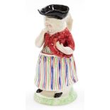 An early 19thC female snuff taker Toby Jug, in standing pose, polychrome decorated with a striped sk