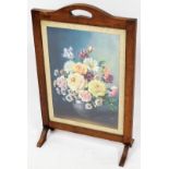 An early 20thC oak framed firescreen, with a floral print to the centre, on shaped scroll legs, 75cm