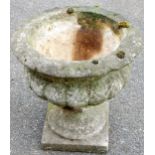 A classical urn stone garden planter, the bellied gadrooned body, on an inverted stem with a circula