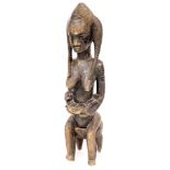 A 19thC heavily carved African tribal figure of a seated lady, with flowing hair on a stool, 98cm hi