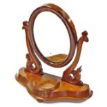 A Victorian mahogany table mirror, the oval glass flanked by floral scroll supports on a shaped base