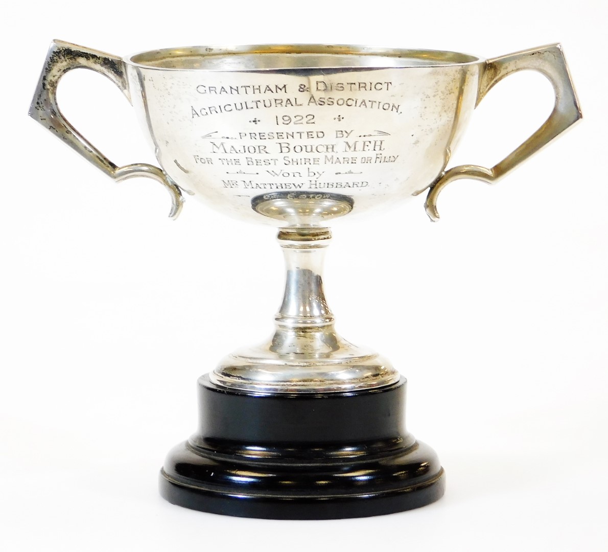 A George V silver trophy, of circular form with ear handles, on a turned stem and circular foot, mar