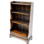 An early 20thC oak waterfall bookcase, of narrow proportion with plain shelves and single drawer ben