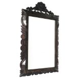 A very early 20thC carved oak mirror, the plain glass in a heavily carved frame, with scrolls, flowe