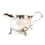 A George V silver cream jug, with flared rim, acanthus capped ear handle and triple hoof feet, Londo