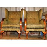 A pair of Parker Knoll style wing armchair, in scroll material on green ground, 99cm high.