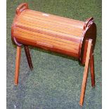 A retro beech cylindrical sewing box on shaped stiles.