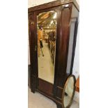 An early 20thC single door wardrobe, with blind fret raised above single mirror, flanked by panels o