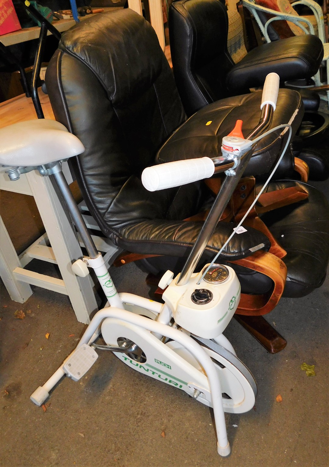 Two similar leatherette swivel armchairs, 100cm high, with footstools and an exercise bike.