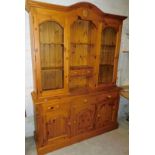 A pine kitchen dresser, with open shelves and two drawers flanked by glazed fronted shelves above a