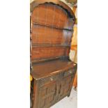 An Ercol style narrow kitchen dresser, with Delft racks above double drawers and double cupboards be