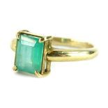 A 9ct gold emerald ring, with square cut cloudy emerald in four claw setting, on a polished plain