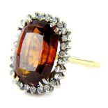 An 18ct gold garnet and diamond dress ring, with central faceted 15.8mm x 12mm x 8.2mm, surrounded