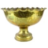 A large brass punch bowl or Monteith, with a petilated border, an hour glass shaped column and domed