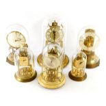 A collection of six various brass anniversary clocks, each in a glass dome, various sizes, makes