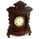 An American Ansonia Clock Company gingerbread type walnut mantel clock, the enamel type dial with